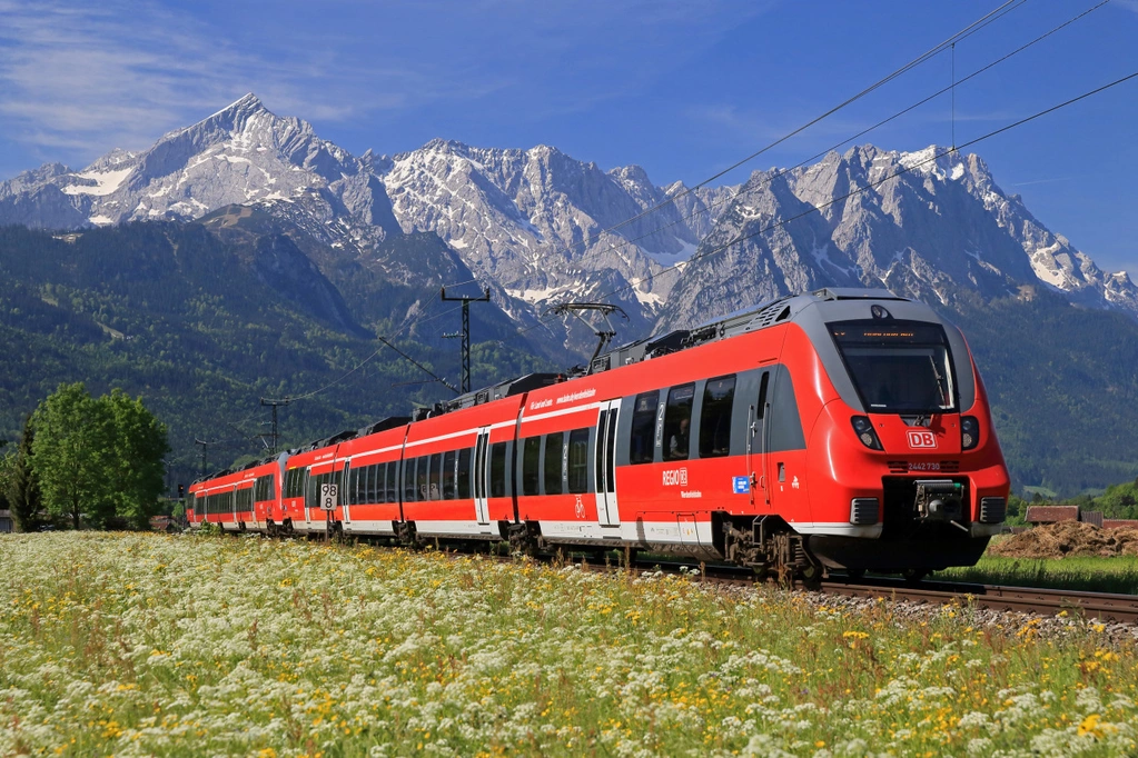  — © Regio Oberbayern unterwegs im Werdenfelser Land: Ein Triebwagen der Baureihe ET 2442 als RB 5408 Innsbruck Hbf -- München Hbf und ein weiterer ET 2442 als RB 5511 Reutte in Tirol -- München Hbf fahren ab Garmisch-Partenkirchen vereinigt in die bayerische Landeshauptstadt. Durch blühende Frühluingswiesen fährt der Zug hier zwischen Garmisch und Farchant vor der herrlichen Kulisse von Albspitze (links) und Zugspitzmassiv (rechts).