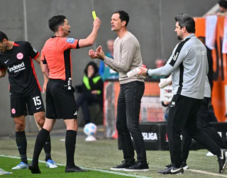 Aufreibender Tag am Spielfeldrand: Frankfurts Trainer Dino Toppmöller (r) bekommt von Schiedsrichter Florian Badstübner die Gelbe Karte gezeigt. — © Jan-Philipp Strobel/dpa