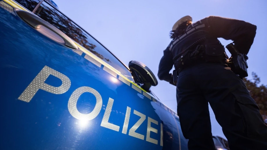 Eine Polizistin steht neben einem Polizeifahrzeug. — © Marijan Murat/dpa